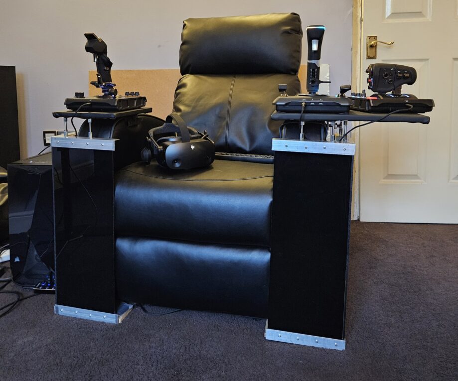 Black lazyboy armchair with HOTASAS attached to arms and VR headset and keyboard on the seat